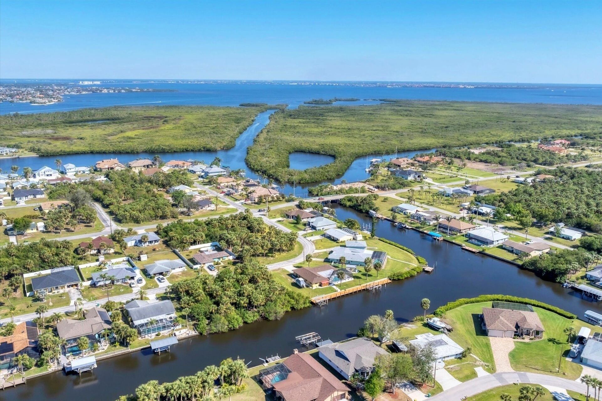 An aerial view of a residential area with houses, a river, and a distant cityscape.