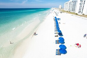 A beach with rows of blue umbrellas and beach chairs, a white sandy shore, and a clear blue sea. - South Bay By The Gulf 021 3 Bedroom Townhouse (Destin)