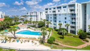A modern hotel with multiple white buildings, a central pool area, and surrounding greenery. - Dolphin Point 406b 2 Bedroom Condo (Destin)