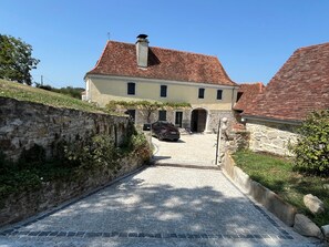 Un chemin de pierres mène à un bâtiment doté d’un toit en tuiles et d’une cheminée.