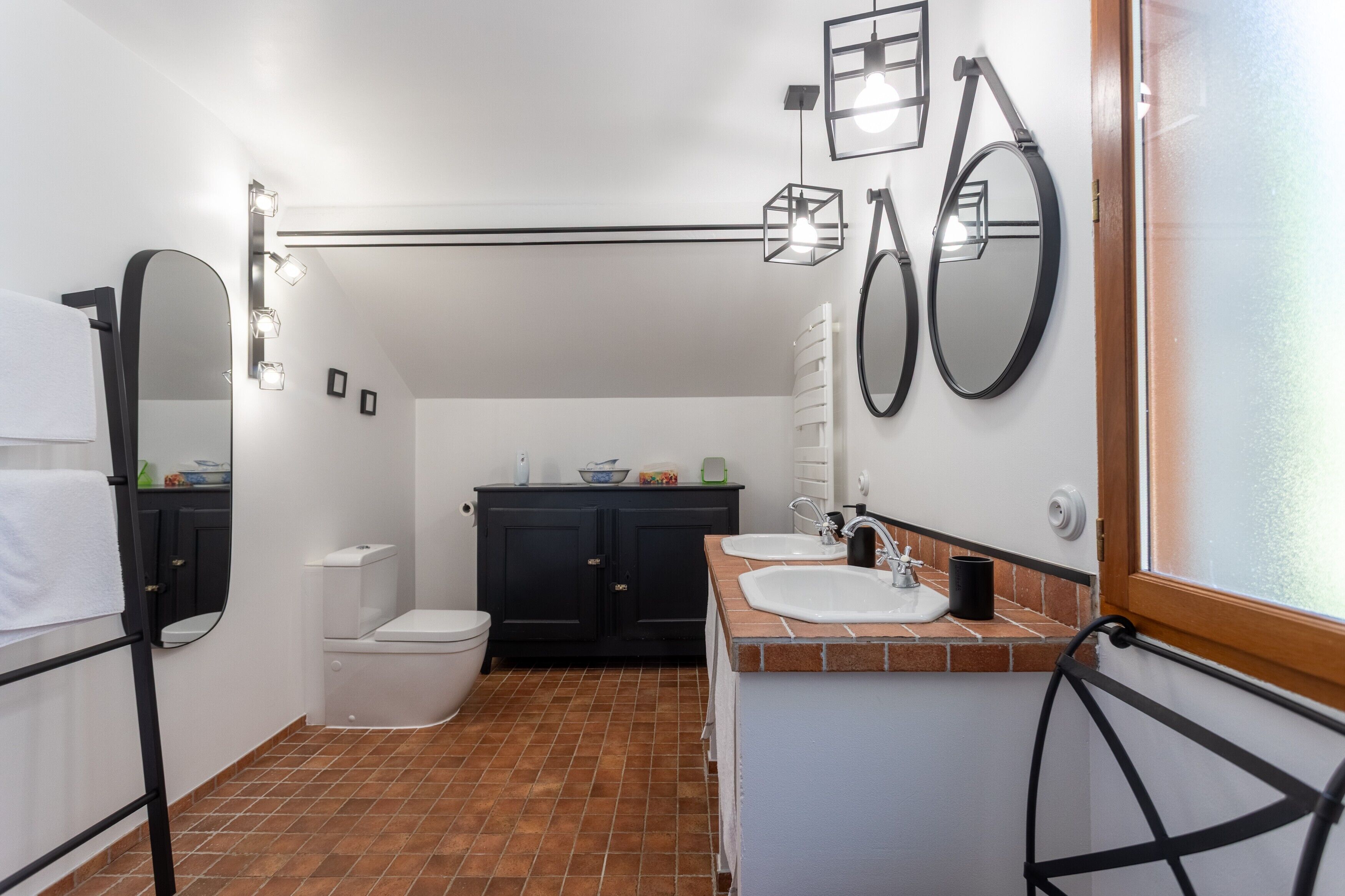 Een badkamer met toilet, wastafel en spiegels.
