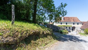 Un paysage rural avec un mur de pierres, un poteau en bois et un bâtiment doté d’un toit en tuiles.