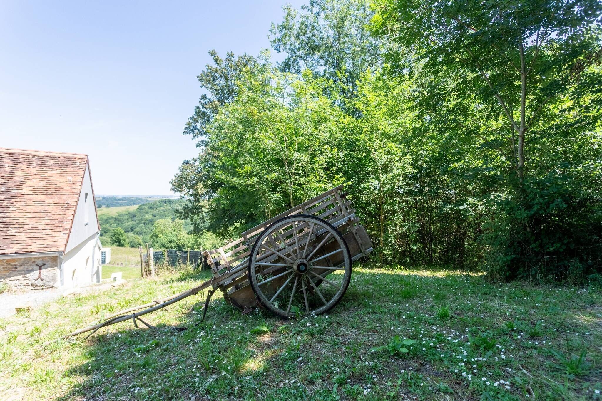 A rural scene with a wooden cart and a white building.