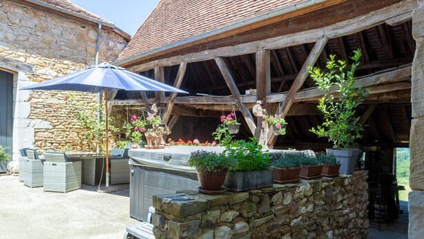 A stone wall with potted plants, outdoor furniture, and a wooden pergola structure. - Guest Room Domaine Cherps Spa & Pool – Serenity (Vielleségure)