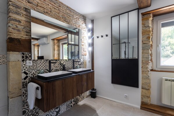 Un baño con pared de piedra, tocador de madera, espejo grande y armario de medicinas negro.