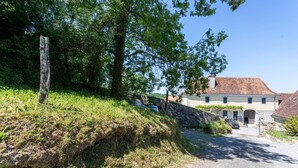 A rural setting with a stone wall, a wooden post, and a building with a tiled roof. - Guest Room Domaine Cherps Spa & Pool – Serenity (Vielleségure)