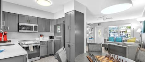 A modern kitchen with grey cabinets, a microwave, a refrigerator, and a red coffee maker.