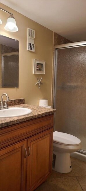 A bathroom with a sink, mirror, vanity, toilet, and shower. - Vantage Pointe #222 1 Bedroom Condo (Daytona Beach)