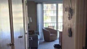 A hallway with a tiled floor leading to a living area with a sofa and a chair. - Vantage Pointe #222 1 Bedroom Condo (Daytona Beach)