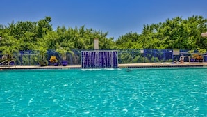 Una piscina con valla azul, rodeada de exuberante vegetación.