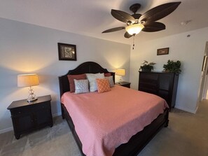 A bedroom with a bed, nightstands, a ceiling fan, and wall-mounted decor. - Kid Friendly Condo With Pool, Basketball, Bocce, Hot Tub, And More! 3 Bedroom Condo (New Smyrna Beach)