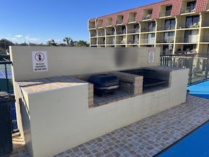Ein Grillbereich am Pool mit einem Schild, das Glasbehälter verbietet.