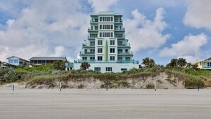 A multi-story hotel with a modern design, located near a beach with a sandy foreground and a clear sky. - Oceanfront Condo With Beautiful Views 2 Bedroom Condo (New Smyrna Beach)