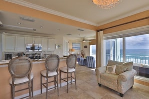 A spacious living area with a view of the ocean, a kitchen with modern appliances, and a seating area with a sofa and chairs. - Oceanfront Condo With Beautiful Views 2 Bedroom Condo (New Smyrna Beach)