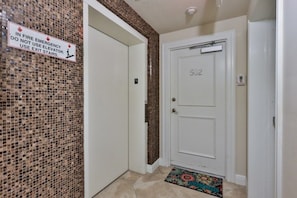 A hallway with a fire emergency sign, a door labeled 502, and a patterned rug. - Oceanfront Condo With Beautiful Views 2 Bedroom Condo (New Smyrna Beach)
