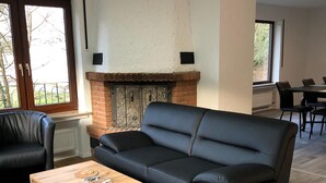 A modern living room with a black leather sofa, a wooden coffee table, and a fireplace. - FeWo Wald Idyllika (Willingen)