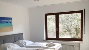 A bedroom with a bed, a window with a view of trees, and a ceiling light. - FeWo Wald Idyllika (Willingen)