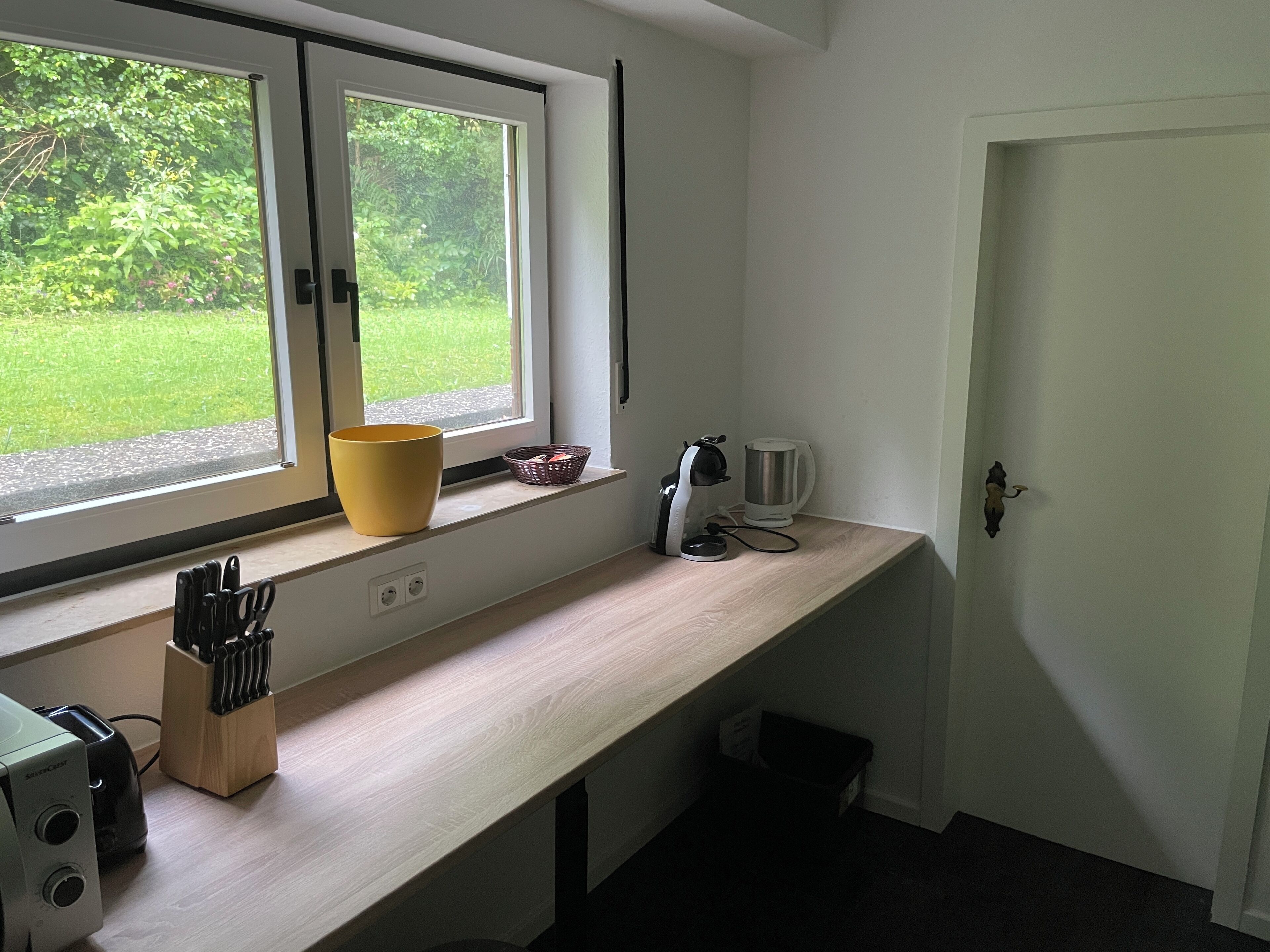 Una cocina con ventana, un tazón amarillo, un hervidor y un tostador.