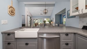 A modern kitchen with grey cabinetry, a stainless steel dishwasher, and a granite countertop. - Beautifully Decorated Townhome In Sugar Mill Nsb 2 Bedroom Townhouse (New Smyrna Beach)