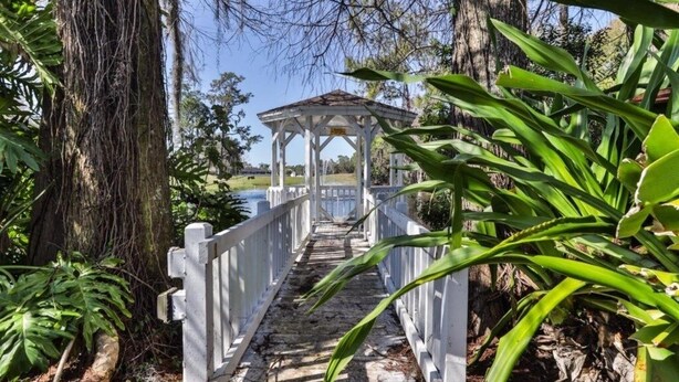 A white wooden bridge leading to a gazebo with a view of the water. - Beautifully Decorated Townhome In Sugar Mill Nsb 2 Bedroom Townhouse (New Smyrna Beach)