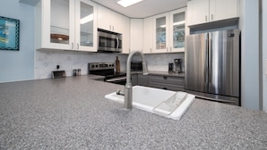 A modern kitchen with white cabinets, stainless steel appliances, and a granite countertop. - Beautifully Decorated Townhome In Sugar Mill Nsb 2 Bedroom Townhouse (New Smyrna Beach)