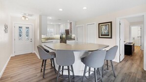 Une cuisine moderne avec des meubles blancs, un réfrigérateur en acier inoxydable et un îlot central doté de tabourets de bar.