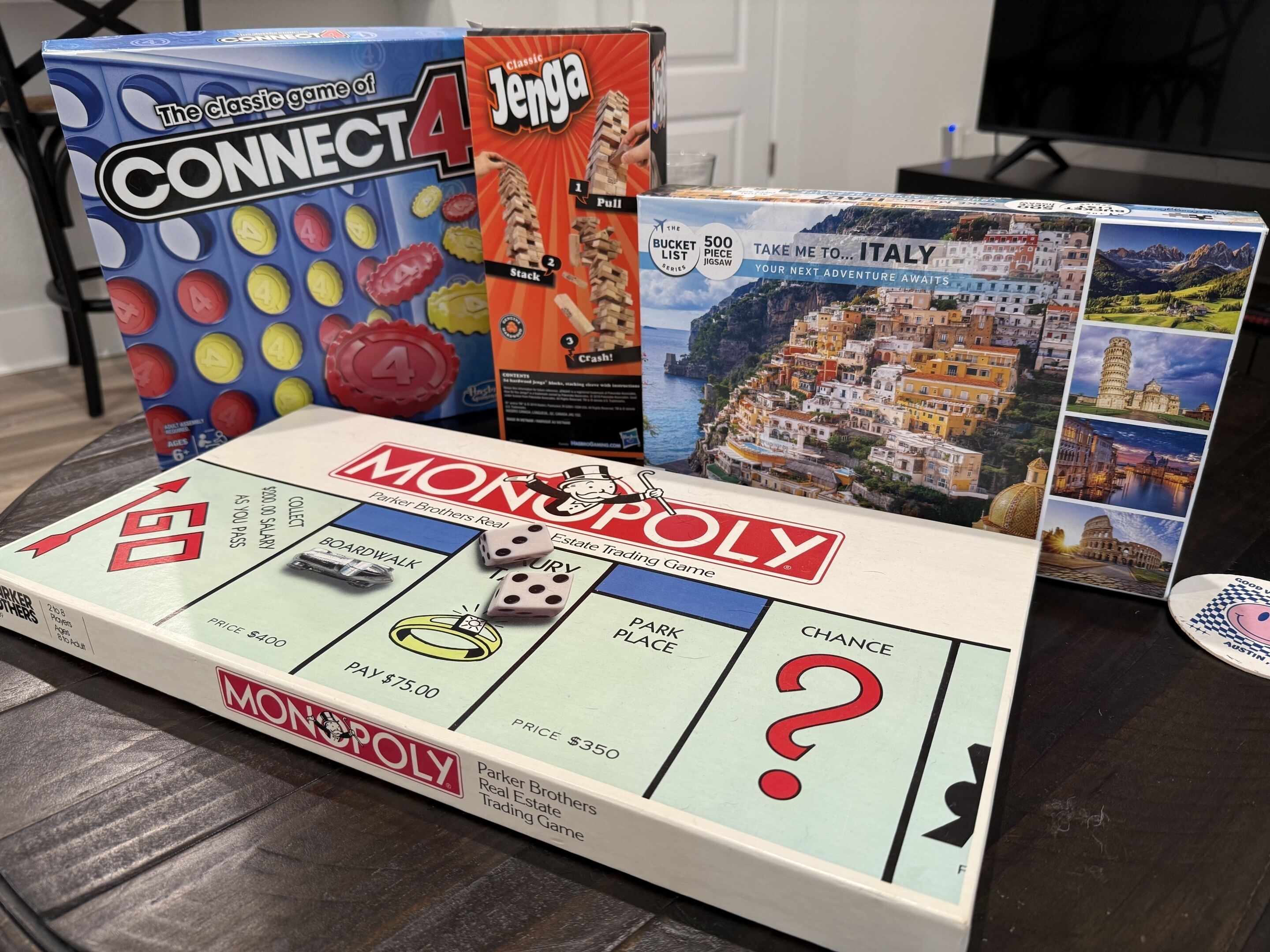 A Monopoly board game with dice and tokens, a Jenga box, and a boardwalk game.
