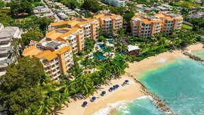 Luftaufnahme eines Resorts mit mehreren Gebäuden, einem Strand und einem Swimmingpool.