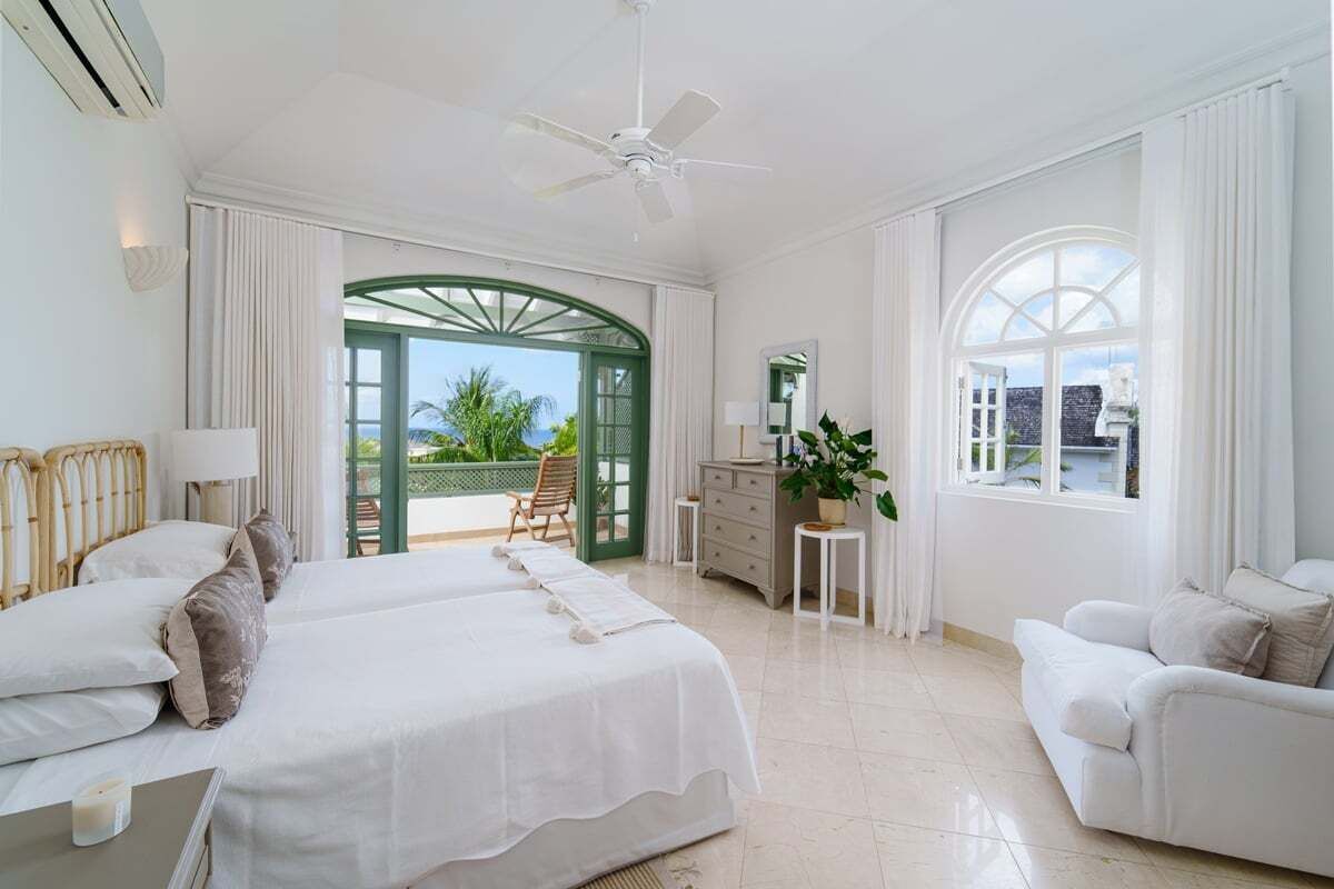 A spacious bedroom with a large bed, a sitting area with a chair, and a view of the outdoors.