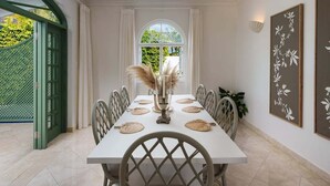 A dining area with a white table set for six, surrounded by chairs with a diamond pattern. A vase with pampas grass is on the table. - Sugar Hill - Jade Vine 3 Bedroom Villa (Holetown)