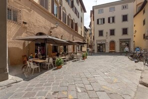 A cobblestone street with outdoor seating at cafes, a bicycle parking area, and a building with a sign reading "CARTOLERIA". - Ponte Vecchio Residence - Comfort & Style in the Heart of Florence (Firenze)