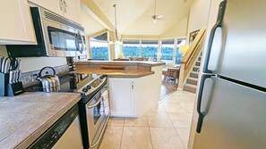 Cozinha com ilha central, eletrodomésticos de aço inoxidável e vista para uma varanda.