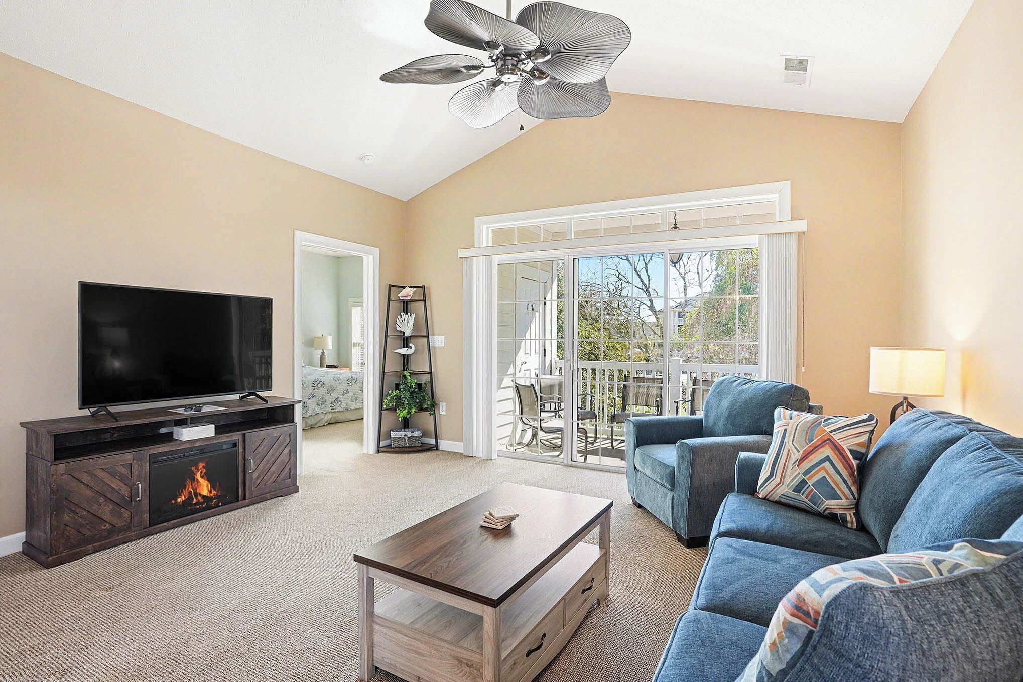 A living room with a TV, fireplace, sofa, and a balcony with a view.