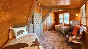 Ein gemütliches Cabin-Interieur mit zwei Betten, einer Treppe und einem Fenster mit Jalousien.