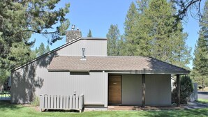 A small, single-story building with a sloped roof, a chimney, and a front door. - Meadow House 58 2 Bedroom Home (Bend)