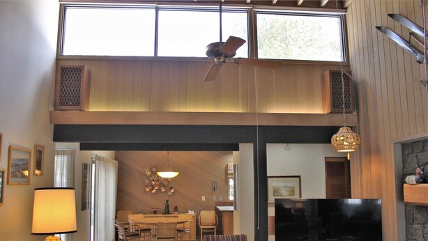 A spacious living area with a high ceiling, a dining table, and a television. - Meadow House 58 2 Bedroom Home (Bend)