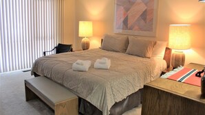 A hotel room with a large bed, two bedside lamps, a bench, and a painting on the wall. - Meadow House 58 2 Bedroom Home (Bend)
