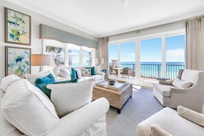 A spacious living room with a large window offering a view of the ocean, a sofa set, and a coffee table. - Adagio C-201 Beach Front 4/3 - NEW to program for 2026! (Santa Rosa Beach)
