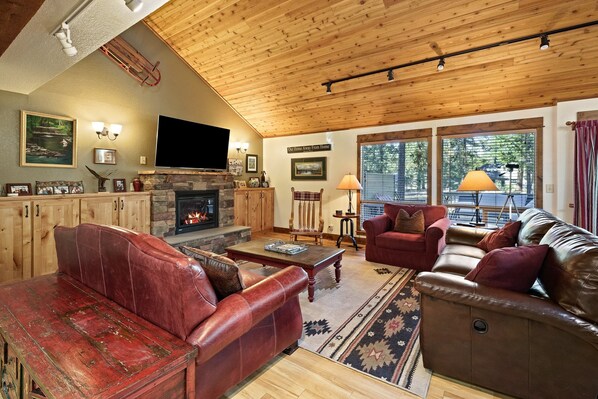 A cozy living room with a fireplace, leather sofas, and a television. - Tamarack 8 3 Bedroom Home (Bend)