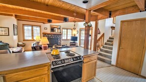 Une cuisine avec des meubles en bois, une cuisinière et une cheminée en pierre.