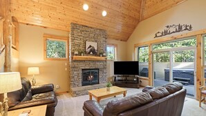 Ein gemütliches Wohnzimmer mit Kamin aus Stein, einer Ledersofa und einem Flachbildfernseher.