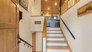 A wooden staircase leading to a kitchen area with a 'welcome' sign and a 'Cabin, sweet cabin' sign. - Tan Oak 2 3 Bedroom Home (Bend)