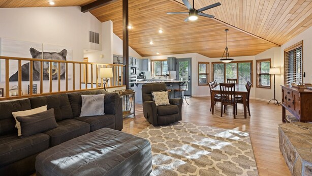 A spacious living area with a wooden ceiling, a large sofa, a dining table, and a kitchen in the background. - Tan Oak 2 3 Bedroom Home (Bend)