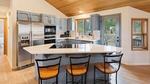 A modern kitchen with a large island, stainless steel appliances, and wooden ceiling. - Tan Oak 2 3 Bedroom Home (Bend)