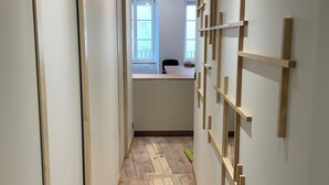 A hallway with wooden flooring, a desk, and a wall-mounted wooden rack. - Cosy apartment in the center of town - Philotée 2 (Clermont-Ferrand)
