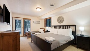 A bedroom with a bed, bedside tables, a desk, and a television. - Yellow Pine 10 5 Bedroom Home (Bend)