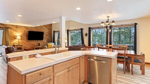 A modern kitchen with wooden cabinets, a stainless steel dishwasher, and a large island with a sink. - Yellow Pine 10 5 Bedroom Home (Bend)