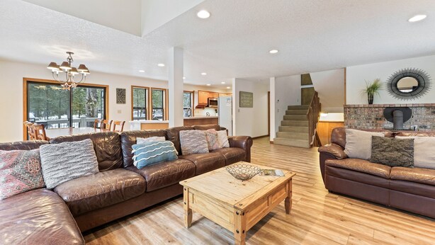 A spacious living room with a brown leather sofa, a wooden coffee table, and a dining area in the background. - Yellow Pine 10 5 Bedroom Home (Bend)