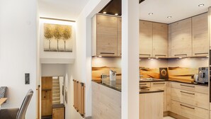 Eine moderne Küche mit Holzschränken, einem eingebauten Backofen und einer Essecke mit Stuhl und Tisch.