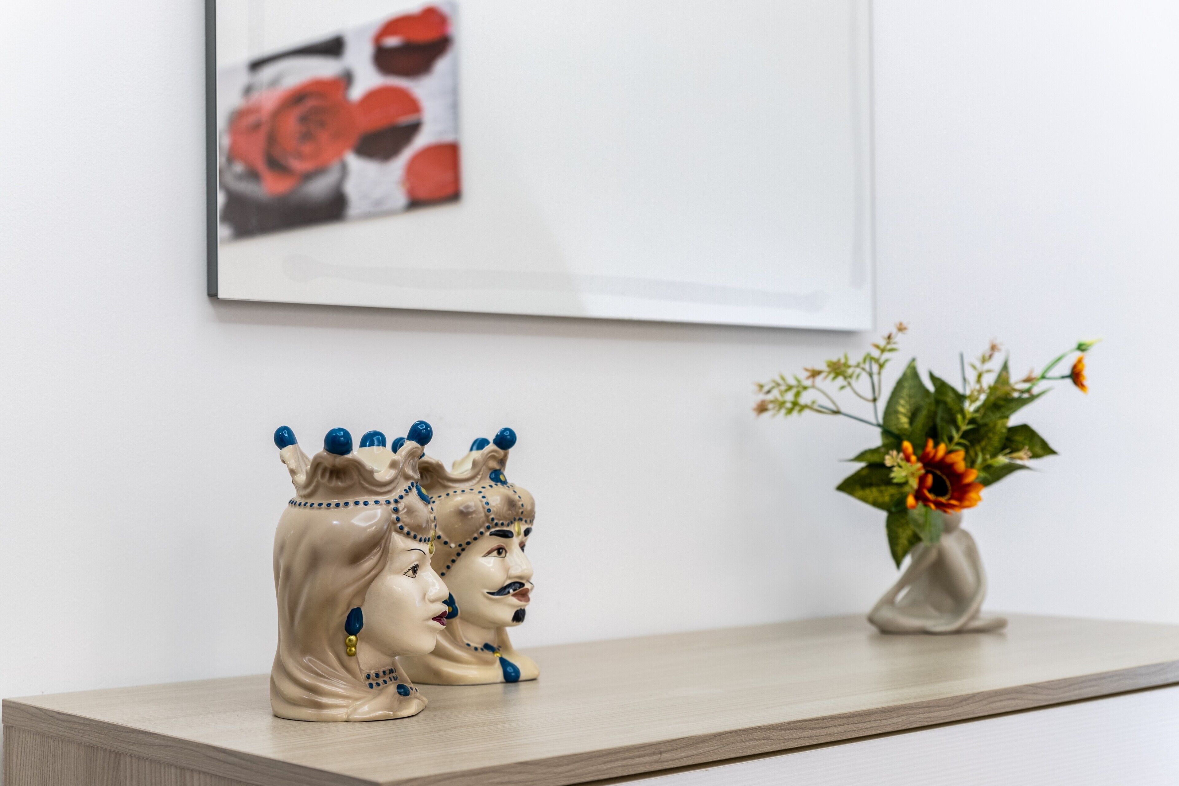 A shelf with two ceramic figures and a vase with flowers.